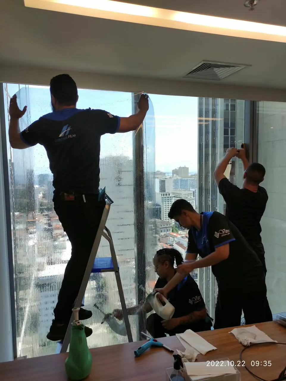 Instaladores aplicando película em janela de escritório em andar alto
